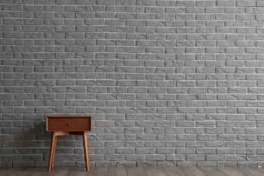 Wooden table with drawer near grey brick wall