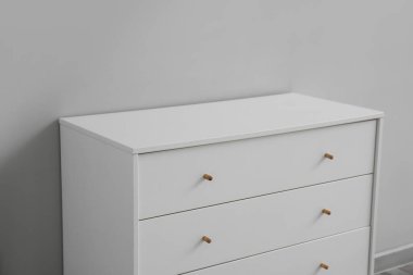 White chest of drawers near grey wall