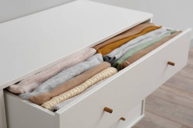 Open drawer with folded clothes in room, closeup