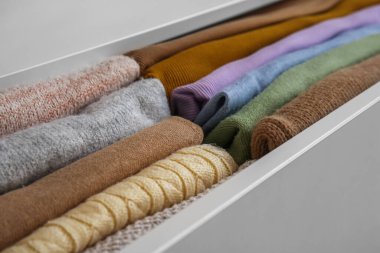 Open drawer with folded clothes in room, closeup