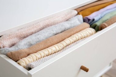 Open drawer with folded clothes in room, closeup