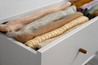 Open drawer with folded clothes in room, closeup