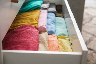 Open drawer with folded clothes in room, closeup