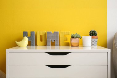 White chest of drawers with decor near color wall in living room