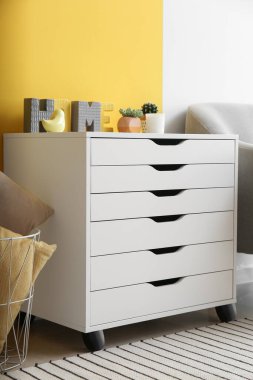 White chest of drawers with decor near color wall in living room