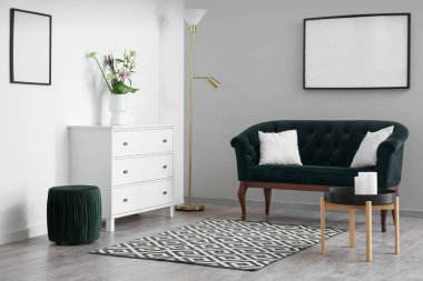 Interior of stylish living room with drawers, flowers in vase and pouf