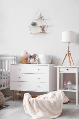 Interior of light children's bedroom with drawers and table