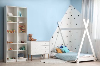 Interior of children's bedroom with drawers, shelving unit and toys