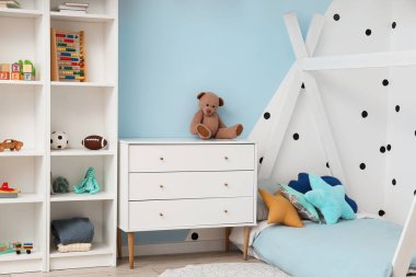 Interior of children's bedroom with drawers, shelving unit and toys