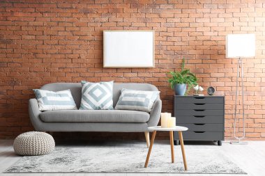 Interior of stylish living room with sofa, blank frame and black drawers