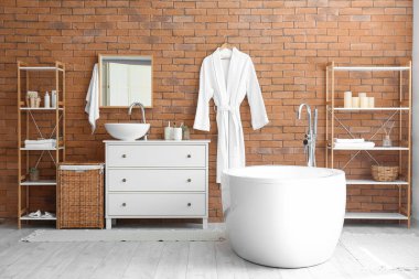 Interior of modern bathroom with drawers, bathtub and shelving units