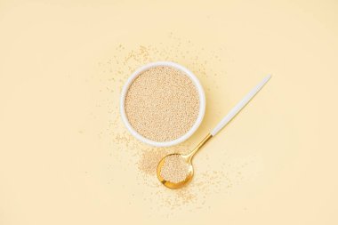 Bowl and spoon with amaranth seeds on color background