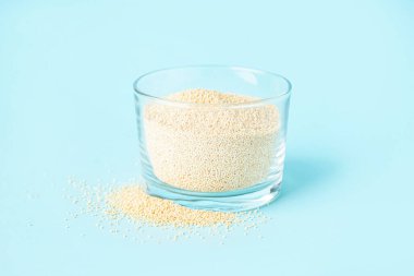 Glass bowl with amaranth seeds on color background