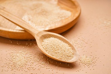 Wooden spoon with amaranth seeds on color background, closeup