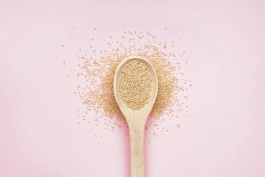 Wooden spoon with amaranth on pink background