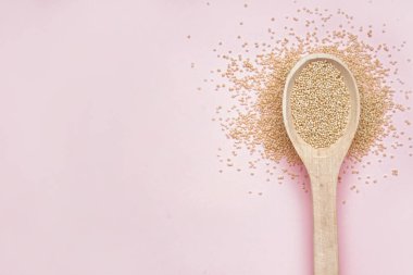 Wooden spoon with amaranth on pink background
