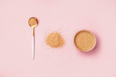 Composition with bowl and spoon of amaranth seeds on pink background