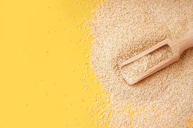 Wooden scoop of amaranth seeds on yellow background