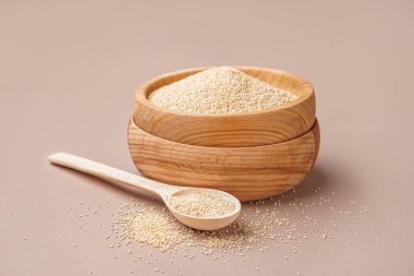 Wooden bowl and spoon of amaranth seeds on color background