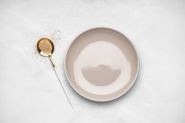 Empty plate and spoon of amaranth seeds on light background