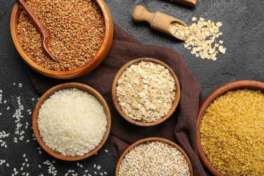 Composition with bowls of different cereals on dark background