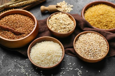 Bowls with different cereals on dark background