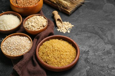 Bowls with different cereals on dark background
