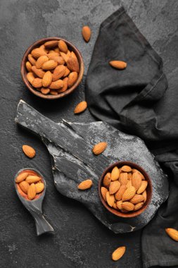 Composition with bowls of tasty almond nuts on dark background