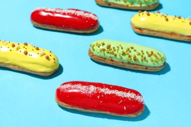 Composition with delicious eclairs on blue background
