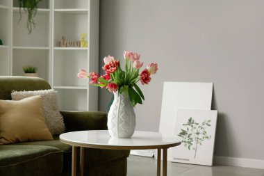 Vase with pink tulips on table in modern living room