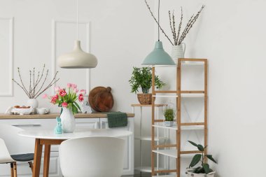 Interior of kitchen decorated for Easter celebration with tulips in vase on dining table