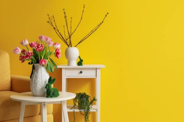 Vase with tulips and Easter rabbit on table in living room