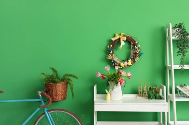 Interior of room decorated for Easter celebration with table, bicycle and tulips in vase