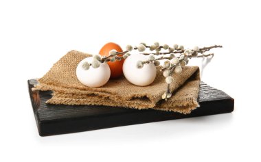 Wooden board with Easter eggs and willow branches on white background