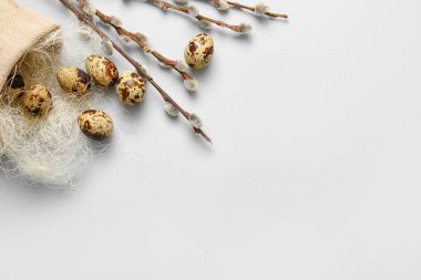 Bag with Easter eggs and willow branches on light background