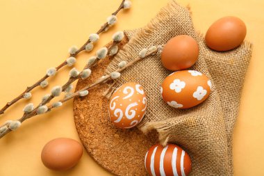 Beautiful Easter eggs and willow branches on color background, closeup