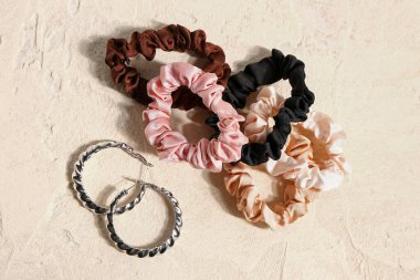 Set of scrunchies with earrings on light background