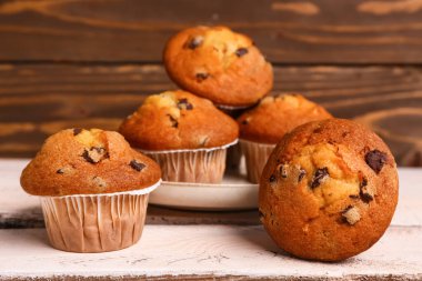 Delicious muffins with chocolate on white wooden table