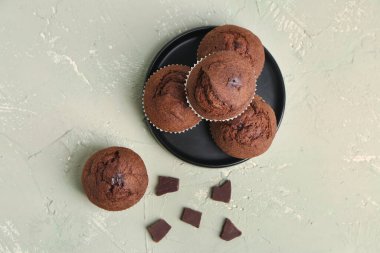 Plate with tasty chocolate muffins on light background