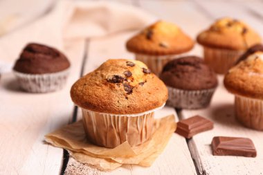 Delicious muffins on light wooden table