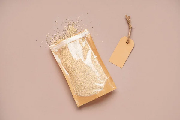 Paper bag with amaranth seeds and tag on color background