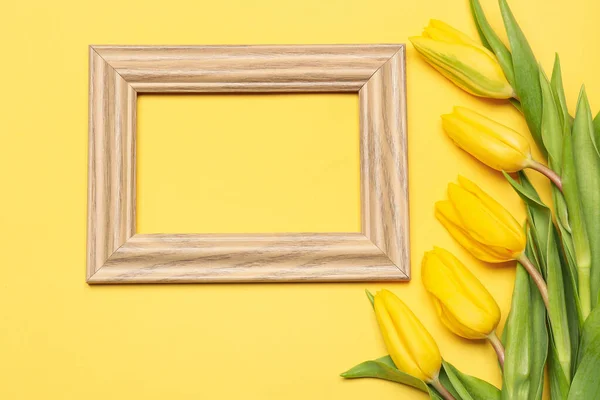 Composition with empty picture frame and fresh tulip flowers on yellow background. Hello spring
