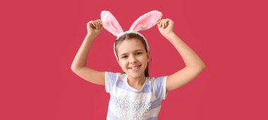 Funny little girl with Easter bunny ears on red background