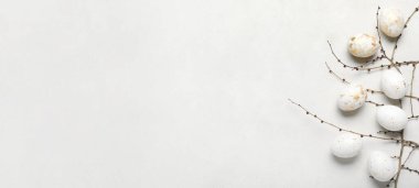 Easter eggs and tree branches on light background with space for text
