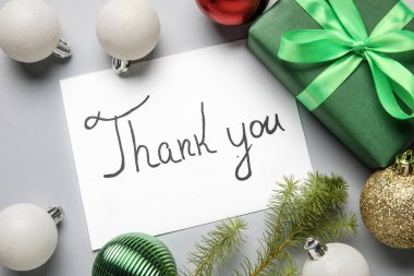 Paper sheet with text THANK YOU, Christmas balls, gift and fir branch on light background