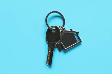 Key with silver house shape keychain on color background