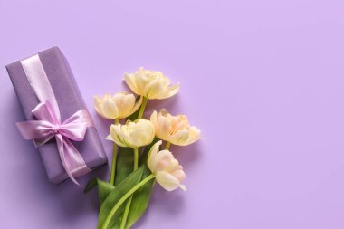 Beautiful tulip flowers and gift box on lilac background