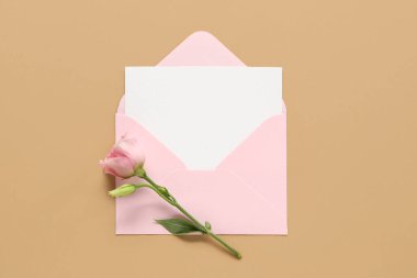 Envelope with blank card and eustoma flower on color background
