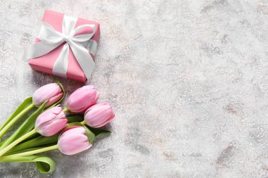 Beautiful tulip flowers and gift box on light background