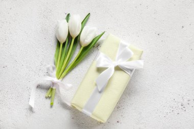 Beautiful white tulip flowers and gift box on light background